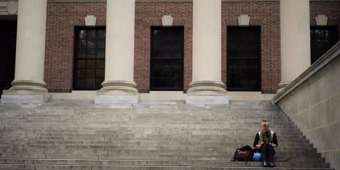 Eine Studentin sitzt auf der Treppe vor einer Universität. (Symbolbild) university of cambridge