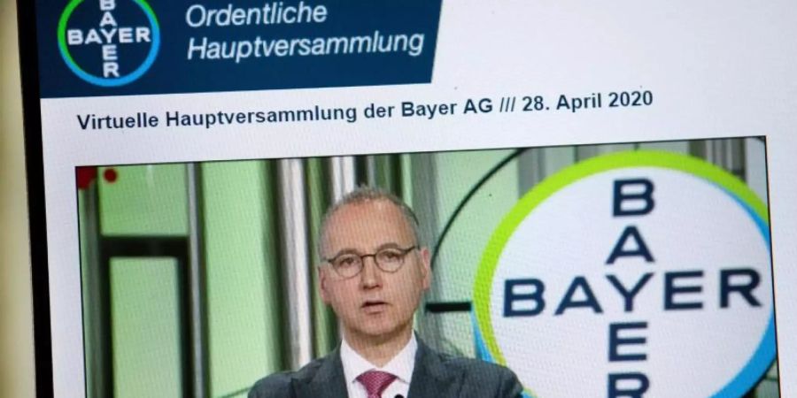 Auf einem Bildschirm ist Bayer Konzernchef Werner Baumann bei seiner Rede zu sehen. Foto: -/Bayer/dpa
