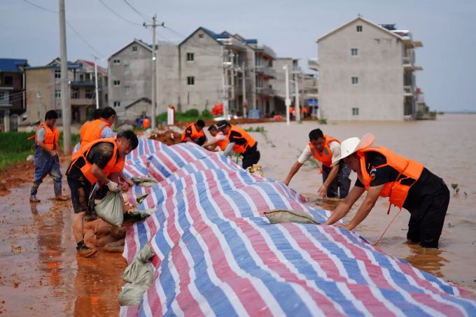 Rettungshelfer errichten einen provisorischen Deich gegen Überschwemmungen in einem Gebiet im Kreis Poyang in der ostchinesischen Provinz Jiangxi. Starke Regenfälle haben in teilen des Landes Gewässer übertreten lassen und Überschwemmungen verursacht. China