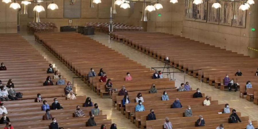 Gläubige sitzen mit Abstand voneinander in einer Kirche in Los Angeles. Kirchen müssen erstmal wieder ihren Betrieb einstellen. Foto: Damian Dovarganes/AP/dpa