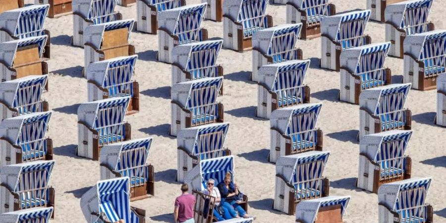 Erste Urlauber sitzen in Strandkörben am Ostseestrand in Warnemünde. Foto: Jens Büttner/dpa-Zentralbild/dpa