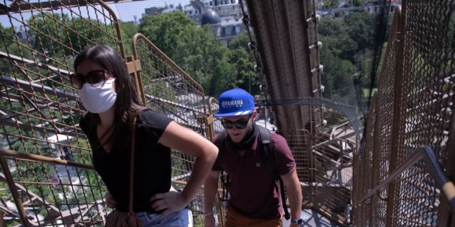 Touristen steigen eine Treppe des Eiffelturms empor. Nach einer über dreimonatigen Zwangspause wegen der Corona-Krise hat der Pariser Eiffelturm am Donnerstag seine Pforten wieder geöffnet. Besucher können zunächst nur über die Treppen den zweiten Stock des Turms erreichen, die Aufzüge sollen erst vom 1. Juli an wieder öffnen. Foto: Andreina Flores/SOPA Images via ZUMA Wire/dpa