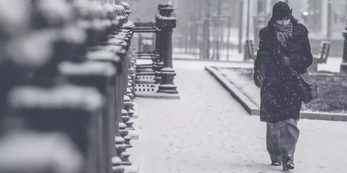 Eine Frau geht einem verschneiten Weg entlang. (Symbolbild) schnee