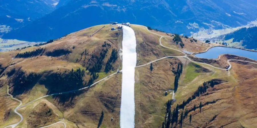 In den Kitzbüheler Alpen ist konservierter Schnee aus dem vergangenen Winter zu einer Piste zusammengeschoben worden. Foto: Expa/Johann Groder/APA/dpa