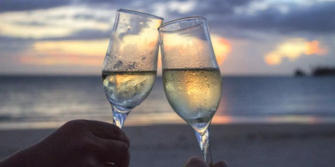 Zwei Personen stossen mit Schaumwein an. Schaumwein