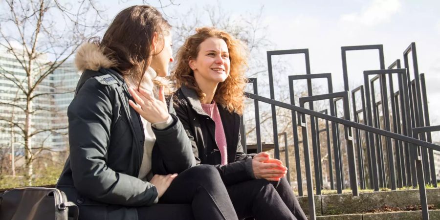 Zwei Frauen sitzen draussen auf einer Treppe.