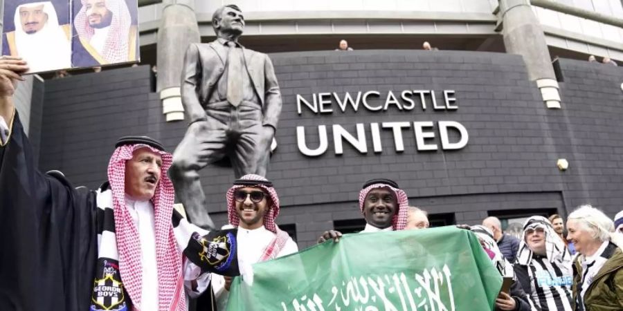 Fans von Newcastle United feiern saudi-arabisch gewandet vor dem Stadion St. James' Park die Übernahme des Clubs durch ein Konsortium. Foto: Owen Humphreys/PA Wire/dpa