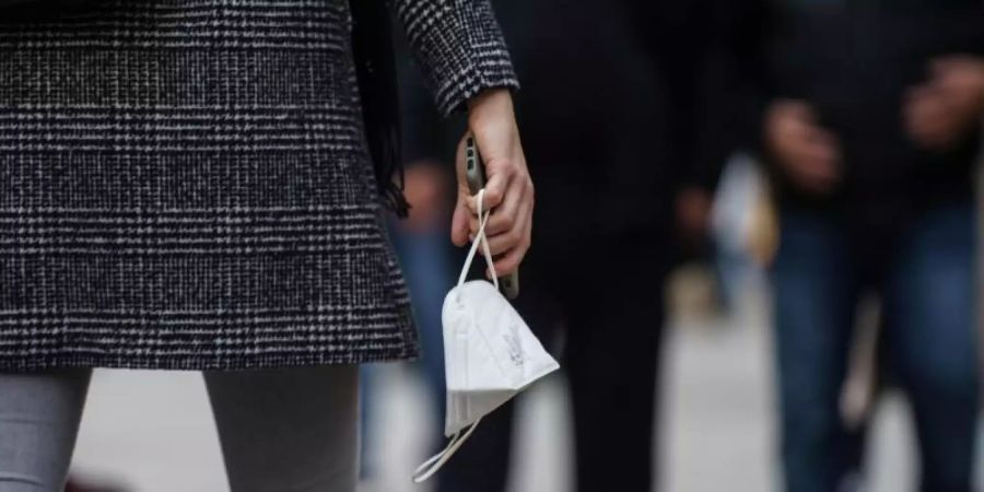 Eine Frau trägt am Nachmittag auf der Frankfurter Einkaufsmeile Zeil eine FFP-2-Maske in der Hand. (Archivbild). Foto: Frank Rumpenhorst/dpa