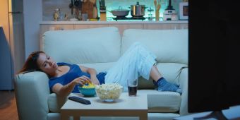 Frau isst vor Fernseher