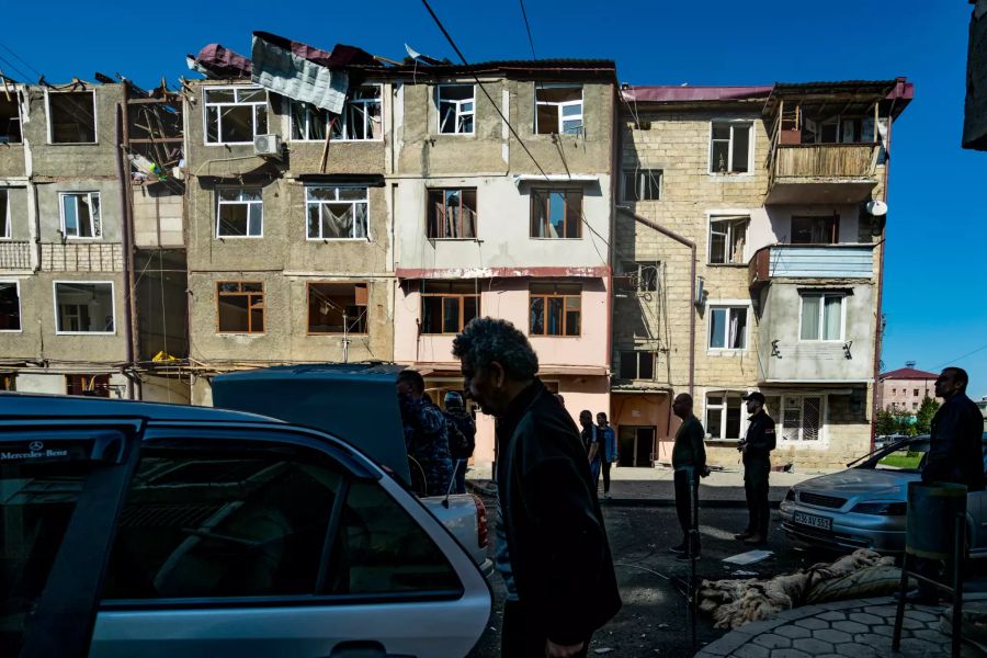 Anwohner stehen vor einem von Beschuss beschädigtem Haus. Seit fast einer Woche liefern sich die Armenien und Aserbaidschan schwere Gefechte in dem von Armenien kontrollierten Gebiet. Foto: Celestino Arce Lavin/ZUMA Wire/dpa