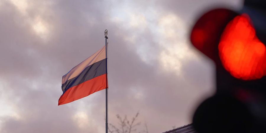 ARCHIV - Die Flagge der Russischen Botschaft weht am frühen Morgen hinter einer roten Ampel. Als Reaktion auf die Ausweisung von deutschen Staatsbediensteten hat die Bundesregierung Russland den Betrieb von vier Generalkonsulaten in Deutschland untersagt. Foto: Joerg Carstensen/dpa