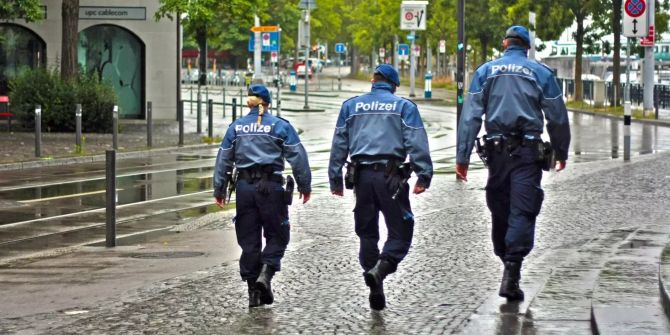 Polizisten laufen eine Strasse entlang.