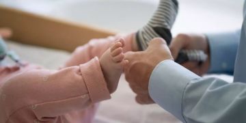 Ein Vater zieht einem Kleinkind socken an.