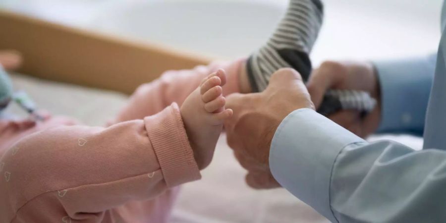 Ein Vater zieht einem Kleinkind socken an.