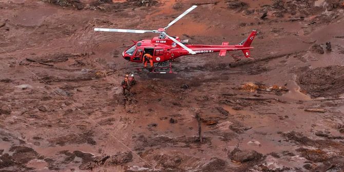 Helfer suchen mit einem Helikopter nach Vermissten im Schlamm.