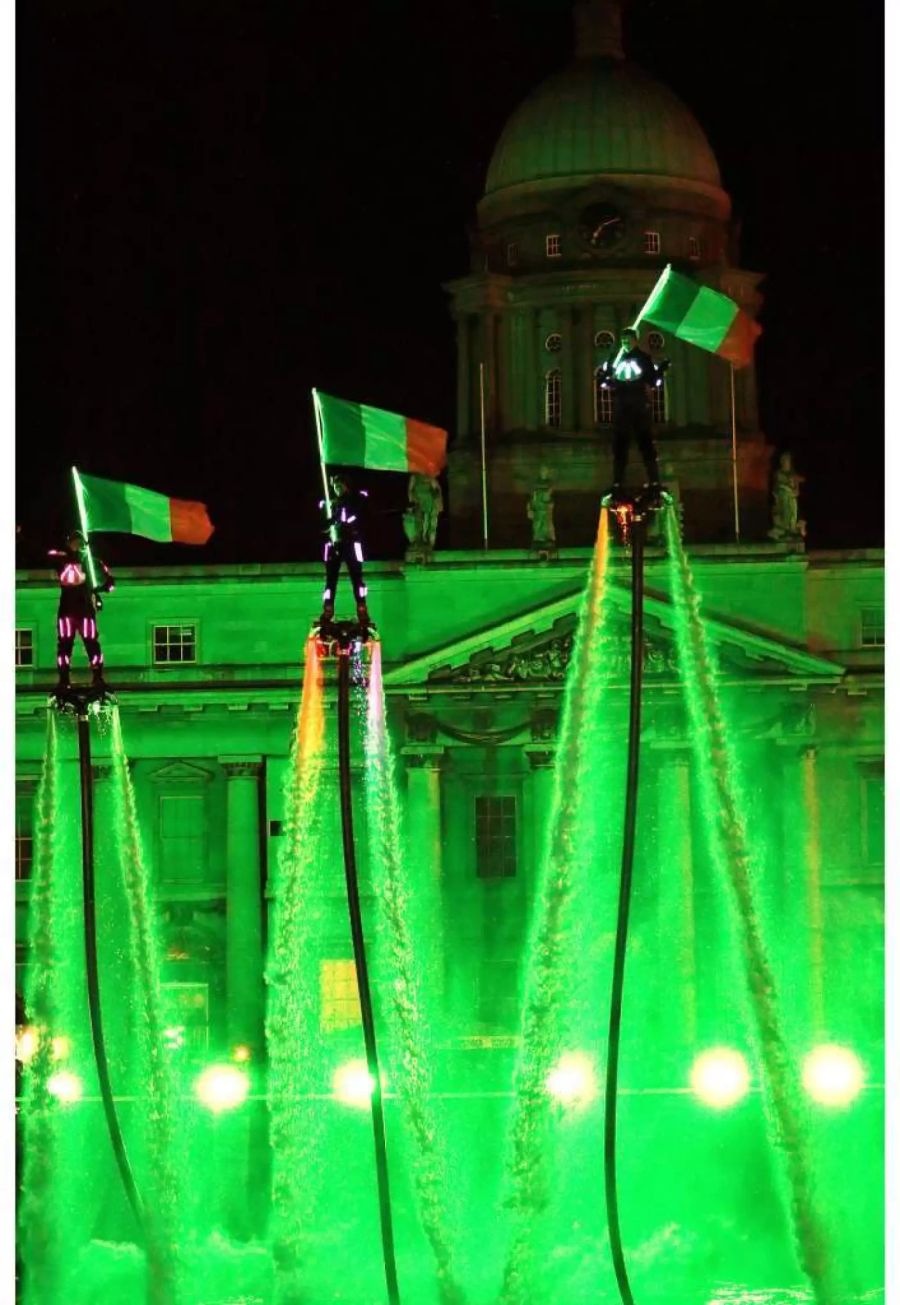 Flyboarder schwenken in Dublin (IRL) bei den Feierlichkeiten zum Jahreswechsel «2018» irische Fahnen.