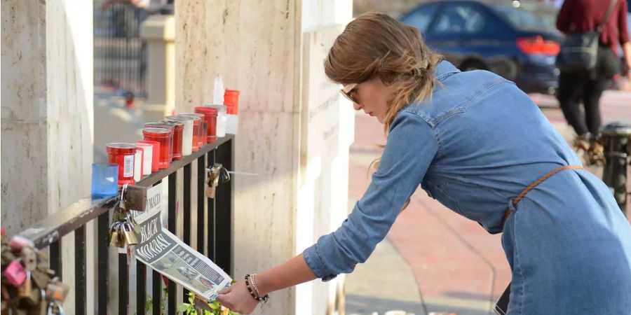 Eine Frau liest die Schlagzeilen einer Zeitung am Denkmal für die ermordete Journalistin Daphne Caruana Galizia auf Malta.