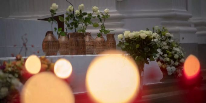 In Solothurn trauern 800 Menschen um die verstorbenen Asylsuchenden. Sieben Wasserkrüge mit einer Rose stehen auf einem Tisch.