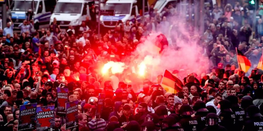 Demonstranten in Chemnitz (D) zünden Pyros im Angesicht der Polizeikräfte.