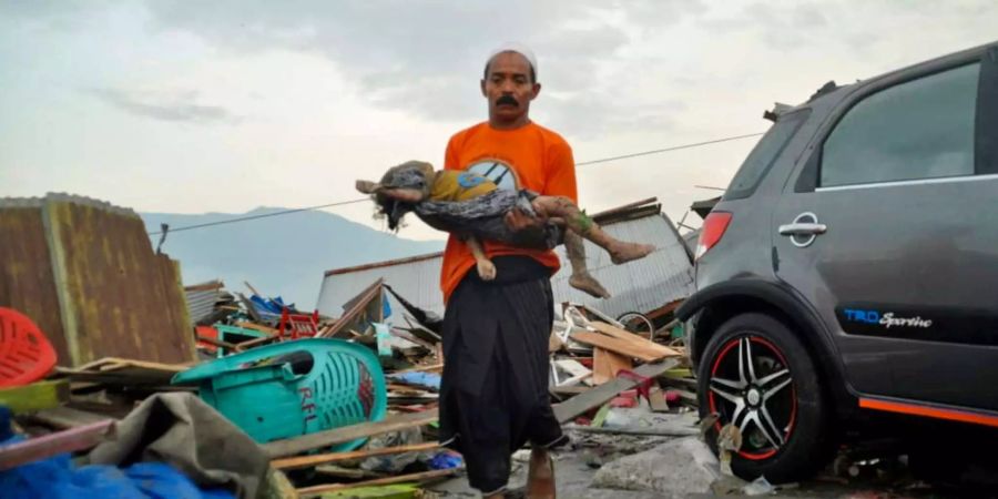 Ein Mann trägt eine Kinderleiche aus den Trümmern nach dem Erdbeben in Palu.