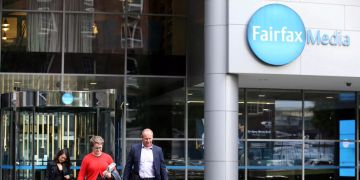 Leute verlassen ein Gebäude von Fairfax Media.