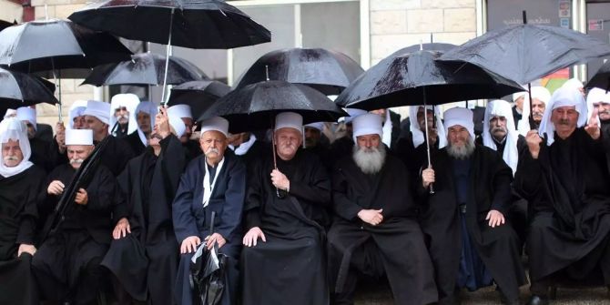 Ein Gruppe von Drusen sitzen in einem Dorf nahe der syrisch-israelischen Grenze bei der Golanhöhe im Regen.