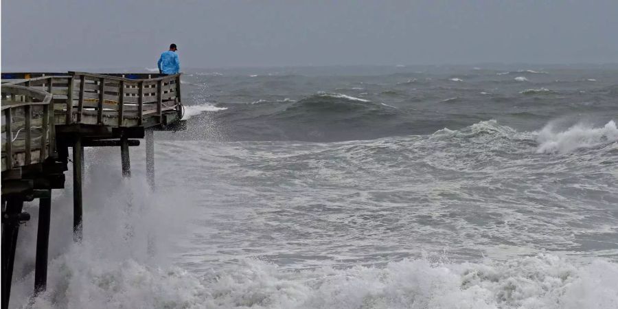 Ein Mann betrachtet die schwere Brandung am Pier, während sich Hurrikan «Florence» trotz verminderter Windstärke mit grosser Zerstörungskraft der Südostküste der USA nähert.