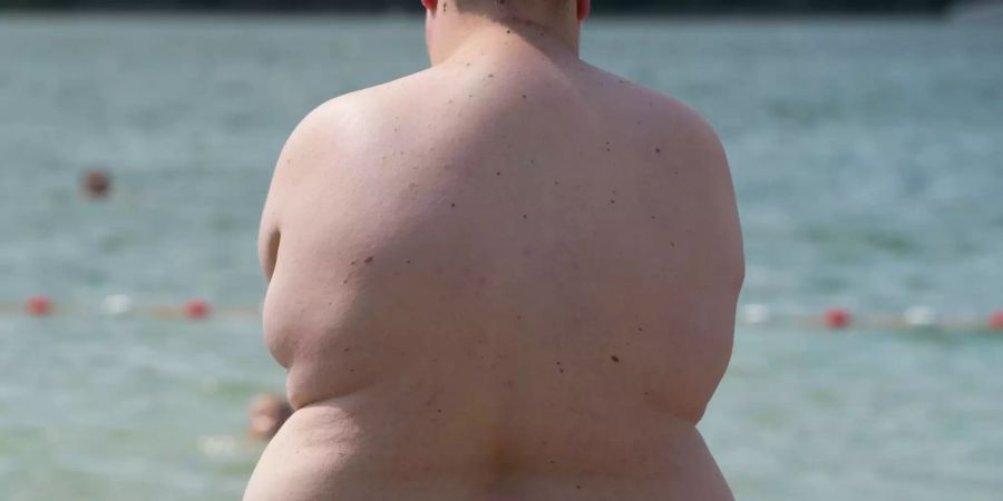 Ein übergewichtiger Junge steht am Badesee Nordstrand am Wasser.