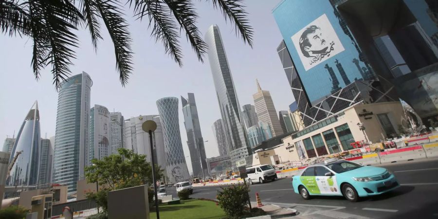 Ein Taxi passiert in Doha ein Gebäude mit einem Bild des Emirs von Katar, Sheikh Tamim bin Hamad Al Thani.