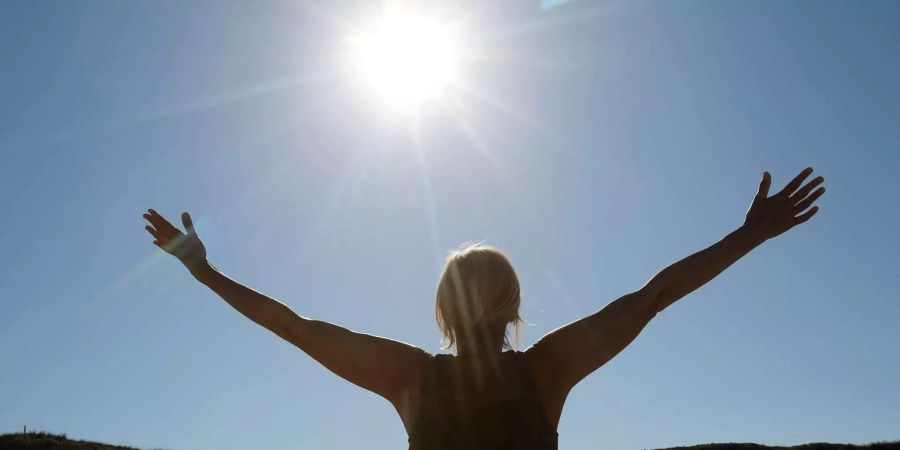 Eine Urlauberin macht bei strahlendem Sonnenschein Yoga-Übungen am Strand von Hörnum.