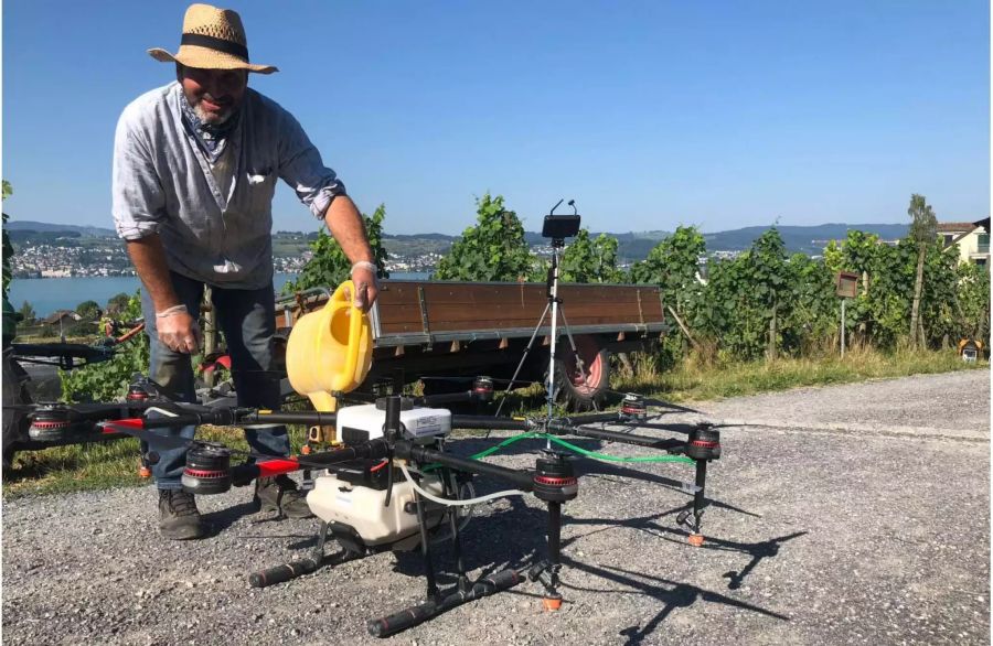 Winzer Domenic Kunz befüllt den 10-Liter-Tank unter der Drohne mit Chemie.