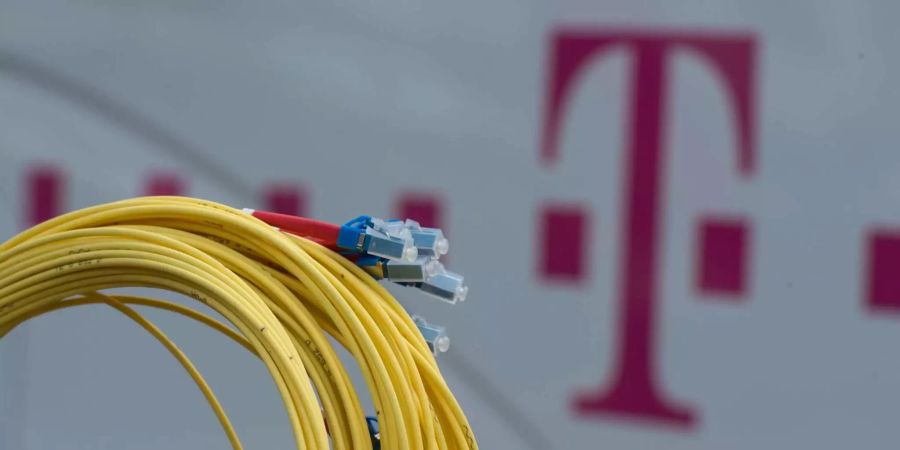 Ein Glasfaserkabel ist vor dem Logo der Deutschen Telekom zu sehen.