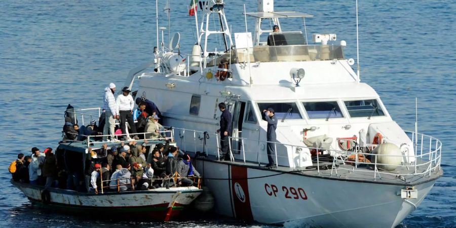 Ein Patrouillenboot der italienischen Küstenwache rettet in den Gewässern der sizilianischen Insel Lampedusa ein überfülltes Boot voll mit Migranten, wahrscheinlich aus Nord Afrika.