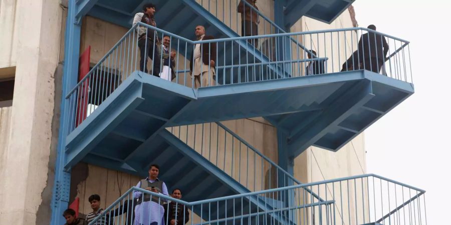 Pakistan, Lahore: Menschen stehen auf Treppen ausserhalb ihrer Büros nach einem schweren Erdbeben.