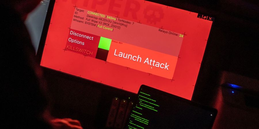 Ein Mann sitzt vor Bildschirmen, die Hacker-Programme und eine fiktive Fernrösch-Software (Wiper) zeigen. Die Gefahr der Online-Erpressung wird nach Einschätzung der Allianz in den nächsten Jahren zunehmen.