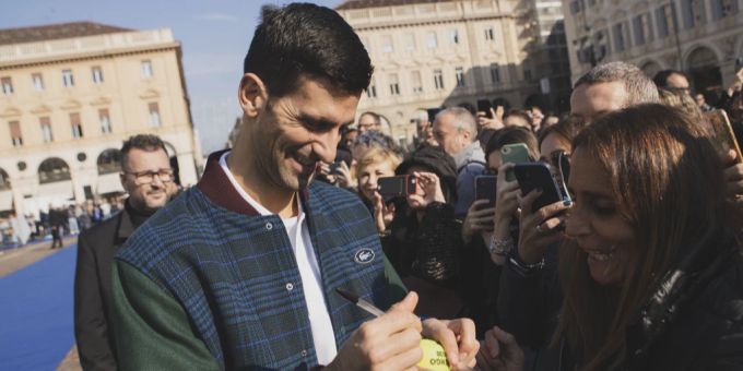 Ein strahlender Novak Djokovic gibt nach seiner Ankunft in Turin Autogramme. novak djokovic