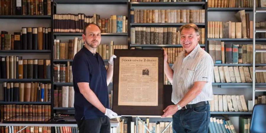 Museumsleiter Roger Münch (r) und Sammlungsleiter Christian Göbel mit der gerahmten Erstausgabe der «Süddeutschen Zeitung». Foto: Oliver Dietze