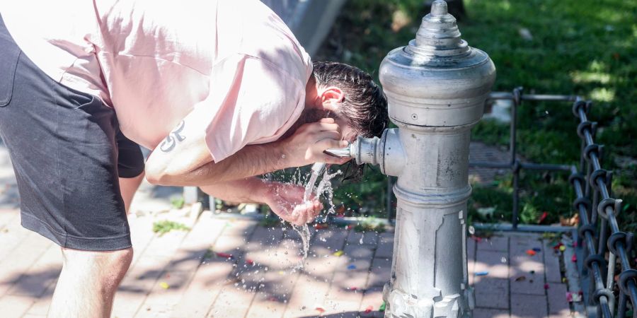 Ein Mann kühlt sich in Madrid an einem Trinkbrunnen ab.