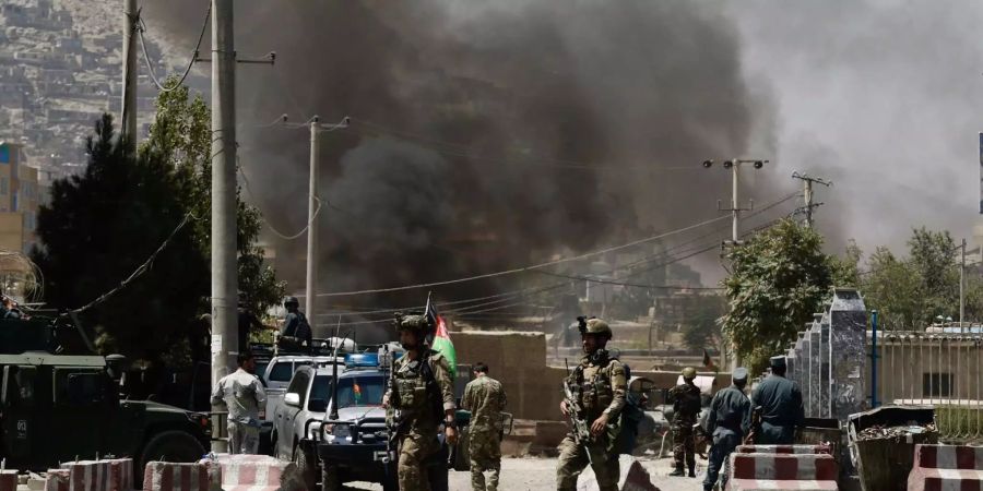 Rauch steigt von dem diplomatischen Viertel in Kabul auf, wo mindestens 20 Raketen des IS einschlugen. Mehrere afghanische Soldaten laufen durch die Strassen.