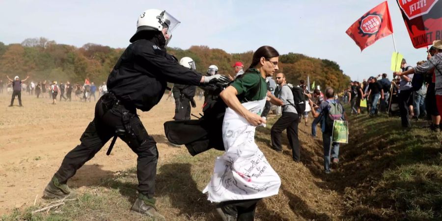 Ein Polizist packt eine Demonstrantin des Hambacher Forst am Kragen.