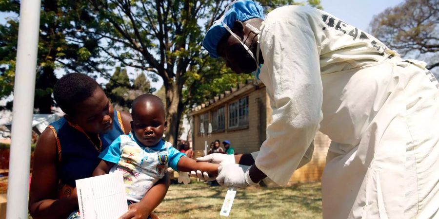 Ein Helfer betreut ein Kind, das an Cholera-Symptomen leidet, in einem Krankenhaus in Harare.