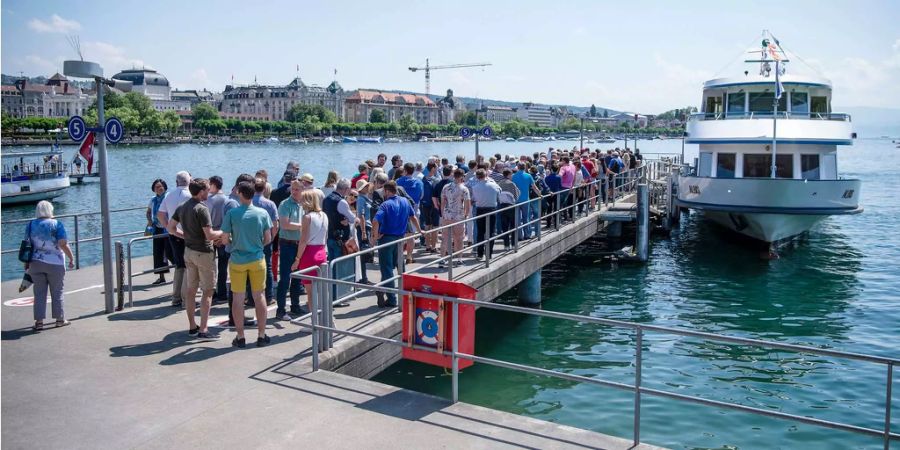 Passagieren warten vor einem Schiff auf dem Zürichsee.