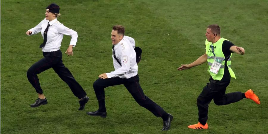 WM, Frankreich - Kroatien, Finalrunde im Luschnikistadion. Eine Sicherheitskraft (r) versucht zwei Flitzer auf dem Spielfeld zu stoppen. Es handelt sich um die beiden Mitglied der russischen Polit-Punk-Band Pussy Riot Pjotr Wersilow (M) und Veronika Nikulschina.