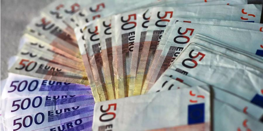 Viele Euro-Banknoten liegen ausgebreitet auf einem Tisch.