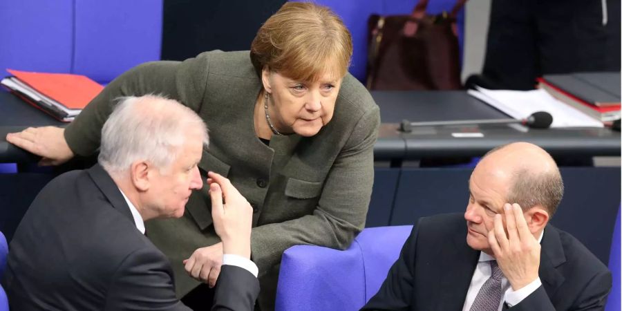 Bundeskanzlerin Angela Merkel (CDU) unterhält sich im Deutschen Bundestag mit Bundesinnenminister Horst Seehofer (l, CSU), und mit Bundesfinanzminister Olaf Scholz (r, SPD).