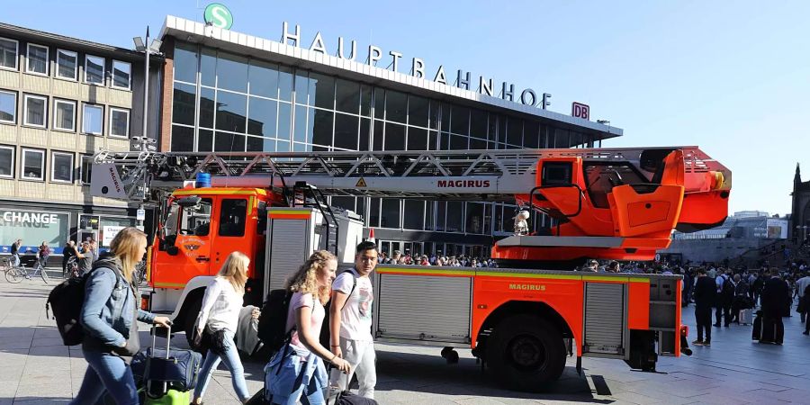 Reisende gehen mit ihren Koffern vor dem Kölner Hauptbahnhof.