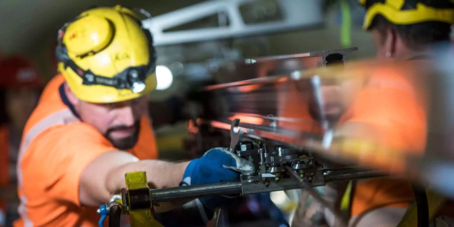Arbeiter bauen eine Deckenstromschiene im Ceneri-Basistunnel ein.