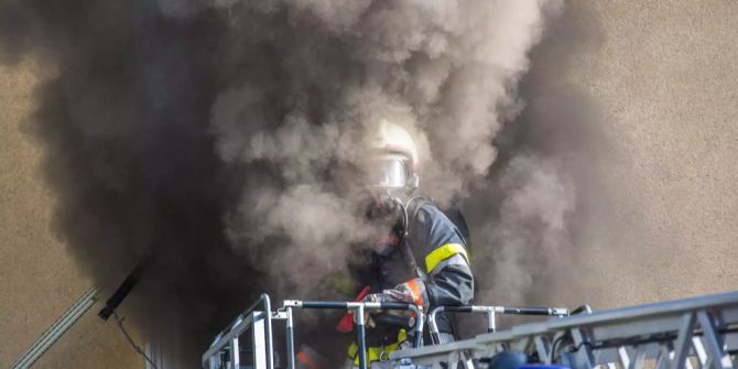 Ein Feuerwehrmann steht im Rauch.