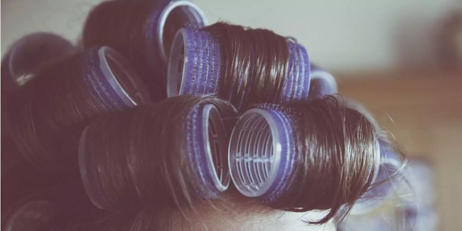 Eine Frau mit Lockenwicklern in den Haaren.