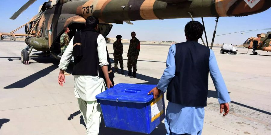 Mitarbeiter der Afghanischen Unabhängigen Wahlkommission tragen eine Kiste mit Wahlmaterial zu einem Hubschrauber auf einem Flughafen in der Provinz Kandahar.